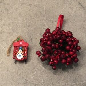Christmas ornaments: one faux red berry wreath and one sled with the name “Bill”
